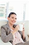 Happy businesswoman drinking a cup of coffee in her sofa