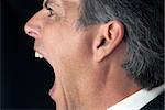 Close-up profile shot of a businessman yelling.