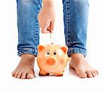 Kid inserting one euro coin on the piggy-bank