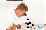 Laboraratory woirk: young smiling researcher looks in microscope