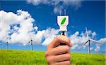 Hand hold eco power plug and Wind turbines on blue sky