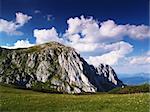Rock with blue sky and clouds and  meadow with fovers