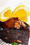 fresh baked delicious chocolate and walnuts cake with slice of orance on top