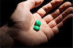 Two green pills on the opened palm