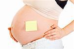 Pregnant woman with blank sticky note on her belly isolated on white. Close-up.