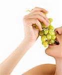 Closeup of woman mouth with green grapes on a white
