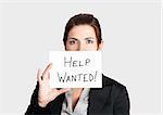 Business woman asking for help holding a cardboard with the text message "Help Wanted"