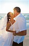 Married couple, bride and groom, kissing at sunset on a beautiful tropical beach wedding