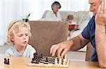 Young boy playing chess with his grandfather at home