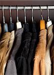 a closeup of some jackets on hangers in a wardrobe