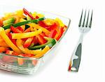 Mix of fresh vegetables from a color paprika in a glass plate on a white background with a plug