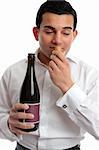 A man sniffing the cork of a bottle of wine.  White background.