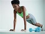 young african american woman in green sportswear exercising with pushups in fitness club, looking at camera. Horizontal shape, side view, copy space