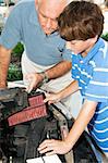 Father teaches his son how to replace the air filter in their car engine.