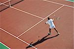 young man play tennis outdoor on orange tennis field at early morning