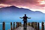 Businessman stand on the pier  and watching the mountain and cloud of sunrise