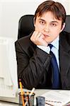 Thoughtful modern business man sitting at desk in office