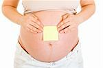 Pregnant woman with blank sticky note on her tummy isolated on white. Close-up.