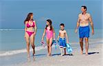 A happy family of mother, father and two children, son and daughter, in swimming costumes having fun in the sea on a sunny beach