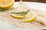 photo of tasty smoked sea bass fish with lemon slices and fennel on it