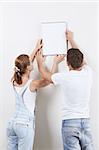 Young couple hanging up painting on the wall