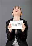 Business woman holding a card board with the text message "Hire me" and begging for a job.