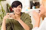 Multi-ethnic Young Attractive Woman Socializing with Friend in Her Kitchen.