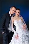 Bride and groom studio portrait over blue background