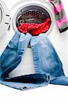 Blue jeans and red shirt hanging out from the door of the washing machine. Space for copy on the floor. Focus is on the lower part of the jeans. Isolated on white background.