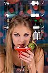 Beauty young woman portrait with a glass drinking a cocktail at a bar