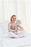 Pregnant woman practicing yoga on her bed