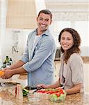 Couple cooking and looking at the camera in the kitchen