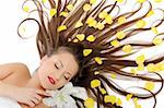 Beautiful spa woman with long healthy hair and bright make-up relaxing on the floor with yellow rose petals. isolated on white background