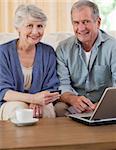 Retired couple looking at their laptop at home