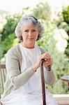 Retired woman with her walking stick at home