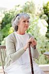 Retired woman with her walking stick at home