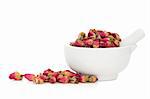 Rose flower buds in a porcelain mortar with pestle and scattered isolated over white background. Used in rose oil and alternative flower remedies.  Rosa damascena