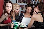 Cute looking young girl with her friends in a cafe discussing a project