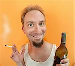 Caucasian man holding a cigarette and a alcohol bottle with a big smile