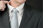 A close-up of a businessman adjusting his collar.