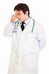 Stressed medical doctor holding fingers at noseband isolated on white