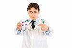 Serious medical doctor pointing finger at pack of pills isolated on white