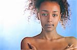 sunny beautiful mulatto woman is looking at camera on sky background