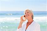 Mature woman listening to her shell