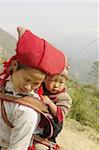 Nearly SAPA, City of North Vietnam. A woman of the ethnic (minority) Hmong Red pompoms with her baby in the back. She wears her beautiful costumes and hairstyle typical. Her baby was also a traditional cap color