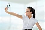 Young attractive business woman looking into a magnifying glass