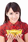 Beautiful asian woman wear cheongsam and holding chinese gold ingot