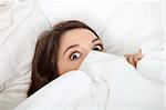 Scared young woman in bed.