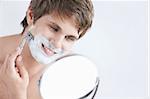 Young attractive man shaves in the mirror