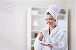 Beautiful girl in a bathrobe and a towel keeps the cup